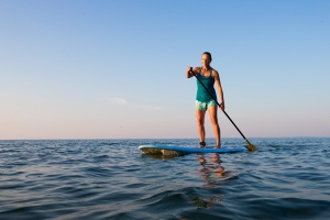 woman paddle boarding after having medicare part c